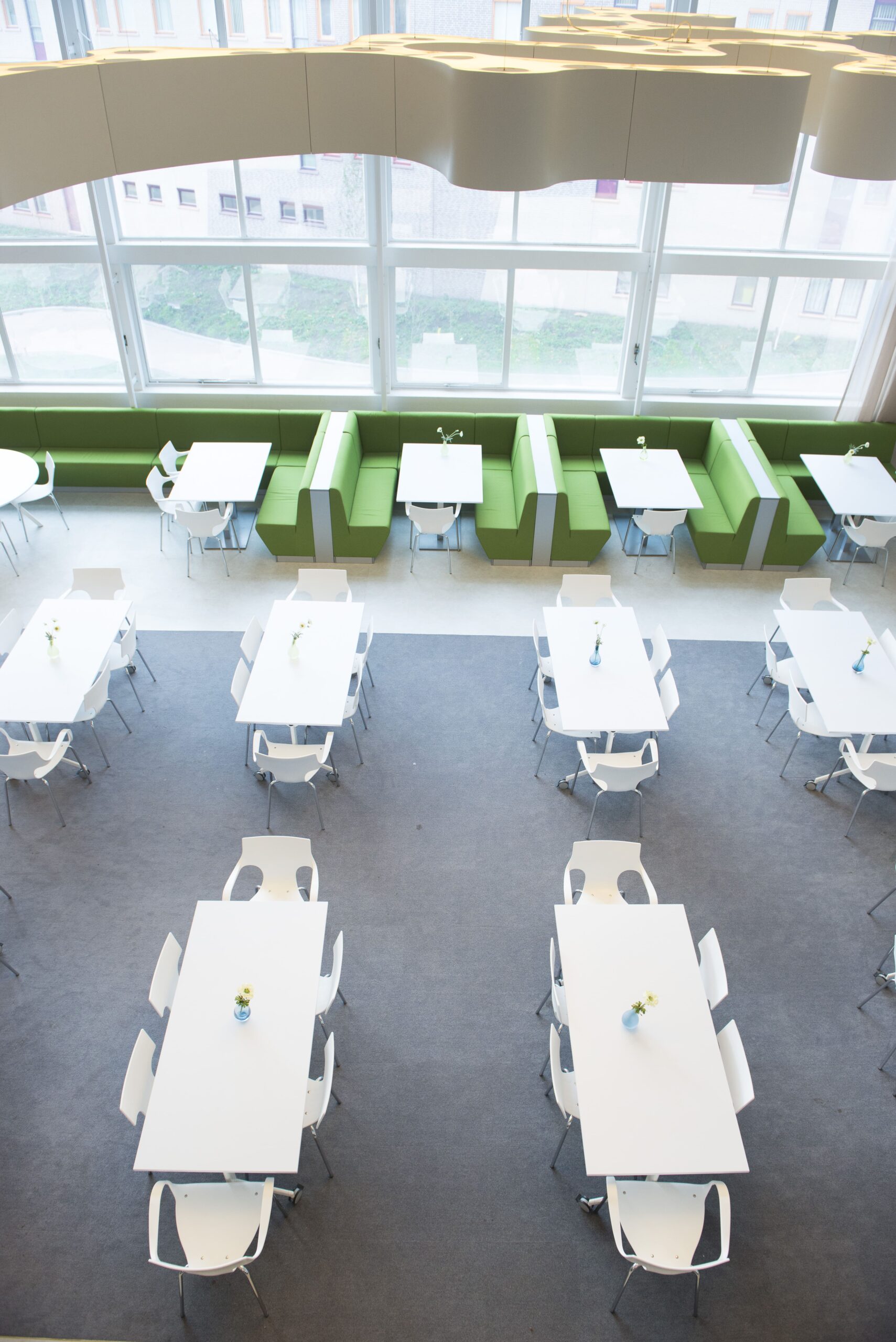 Bovenaanzicht van de ruimte in het Isala Ziekenhuis met groene banken en witte tafels en stoelen.