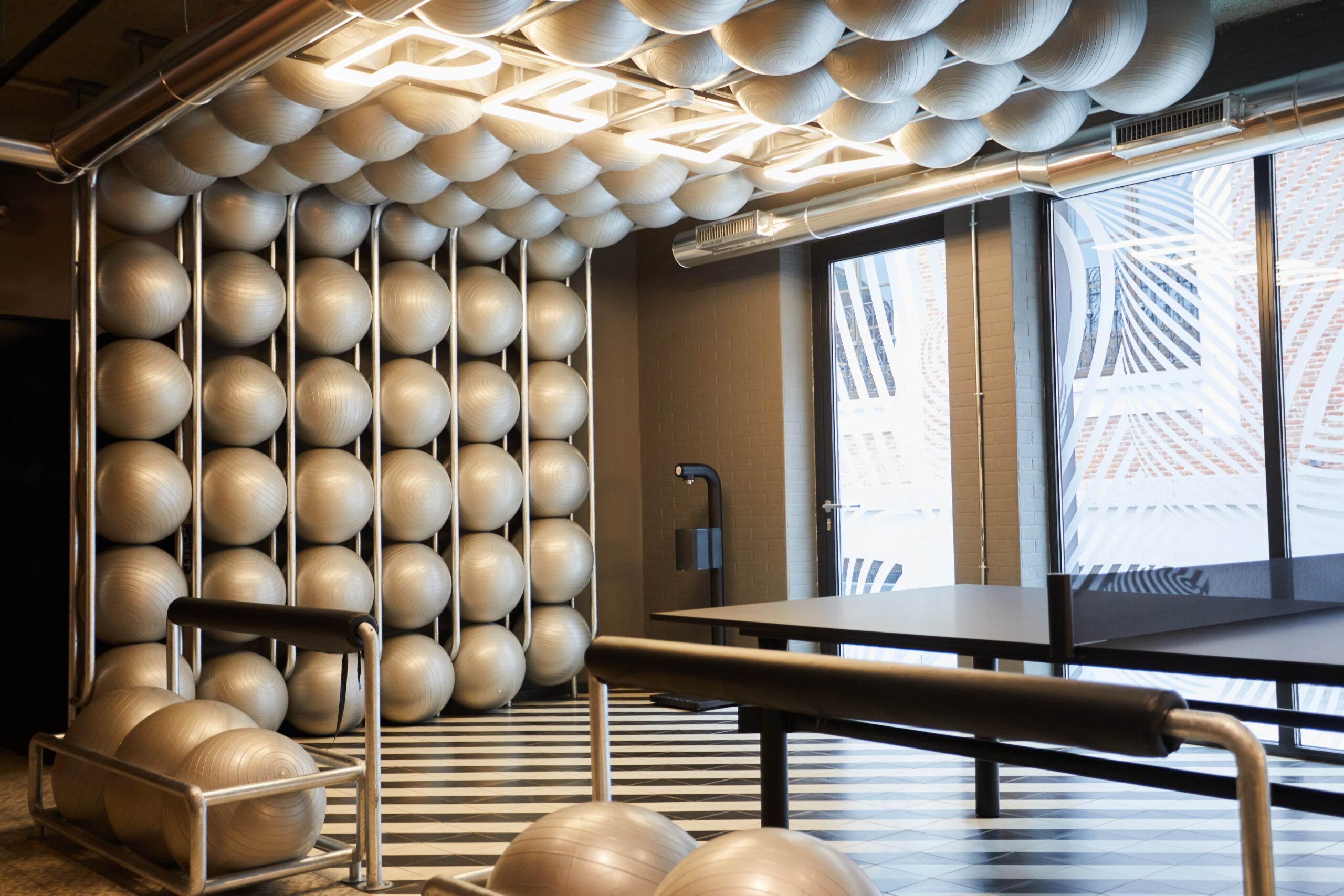 Ruimte met ping pong tafel met daaromheen yoga ballen ter decoratie.