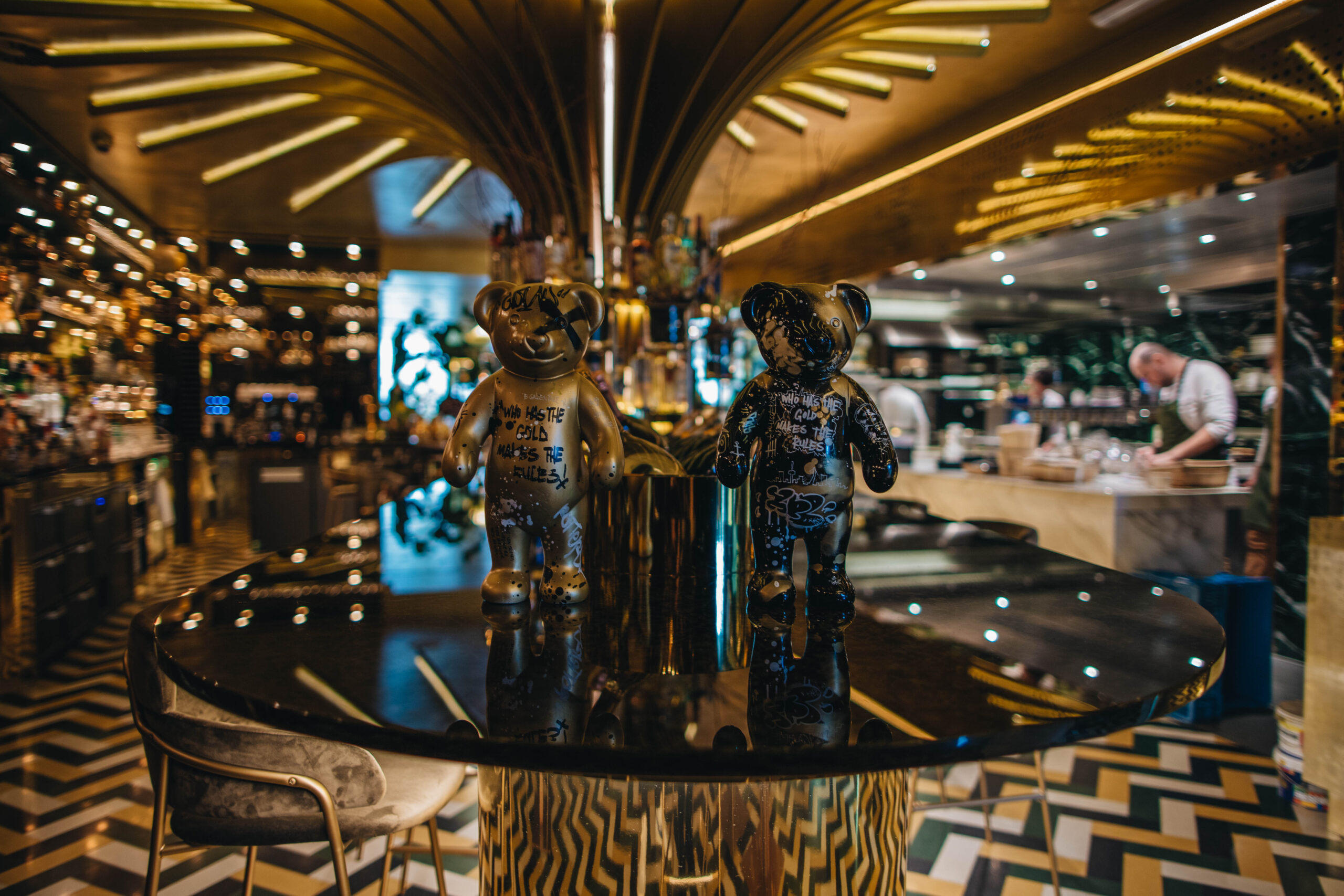 Twee standbeeldjes van gouden teddyberen op de rand van de bar in Restaurant GOUD in Rotterdam